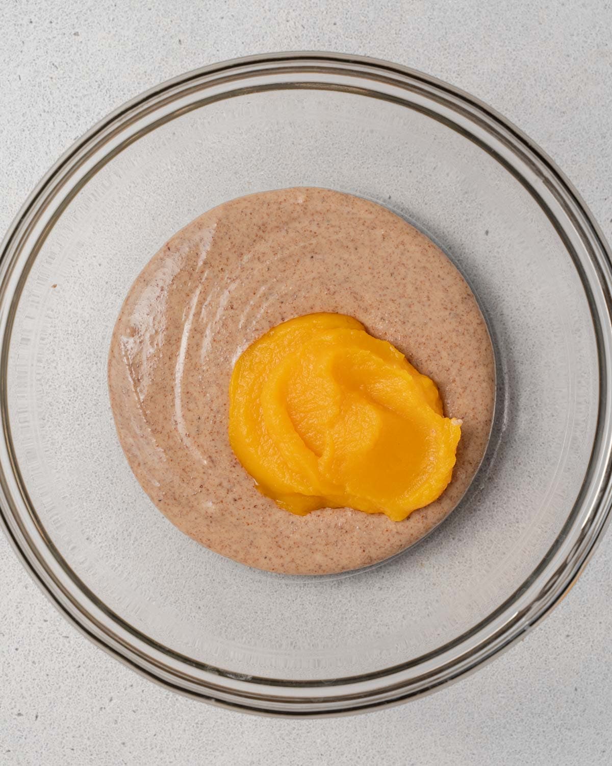 pumpkin puree added over almond butter in a  bowl.