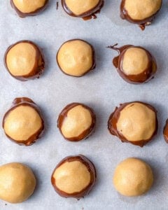 dipping the peanut butter balls in melted chocolate and adding to sheet pan.