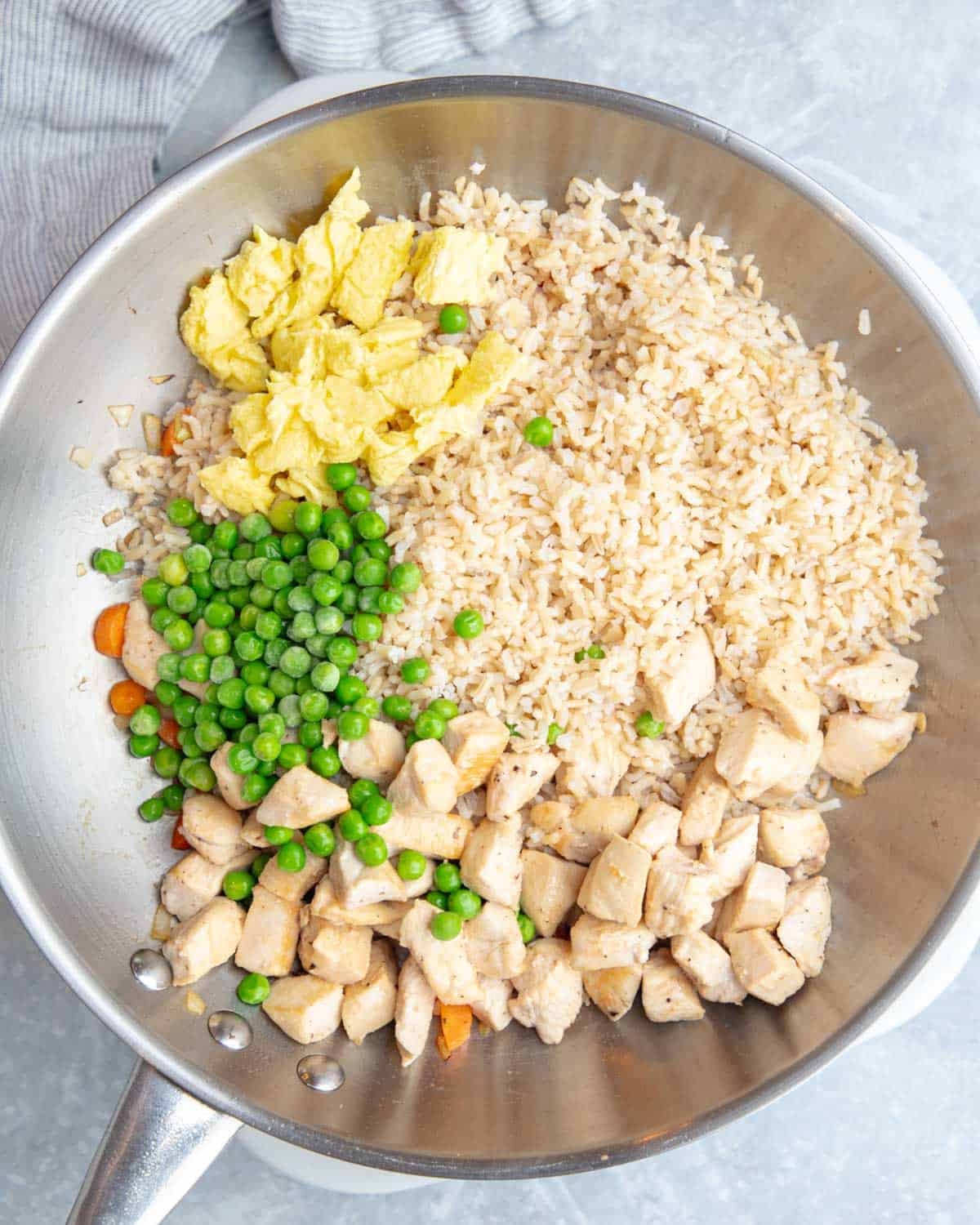Rice, chicken, veggies, and eggs, added to a pan.