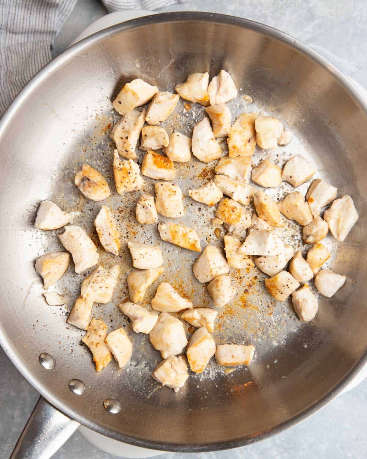 Seared chicken bites in a pan.