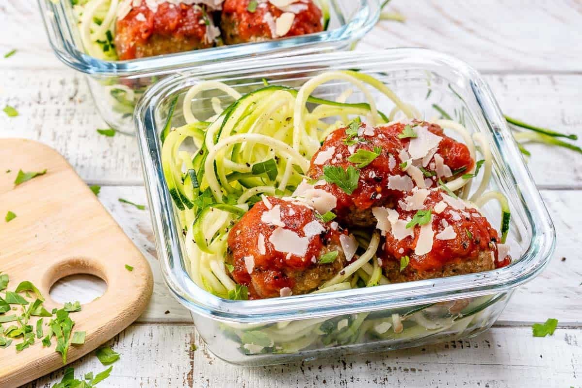 a glass bowl with zoodles and turkey meatballs with marinara sauce.