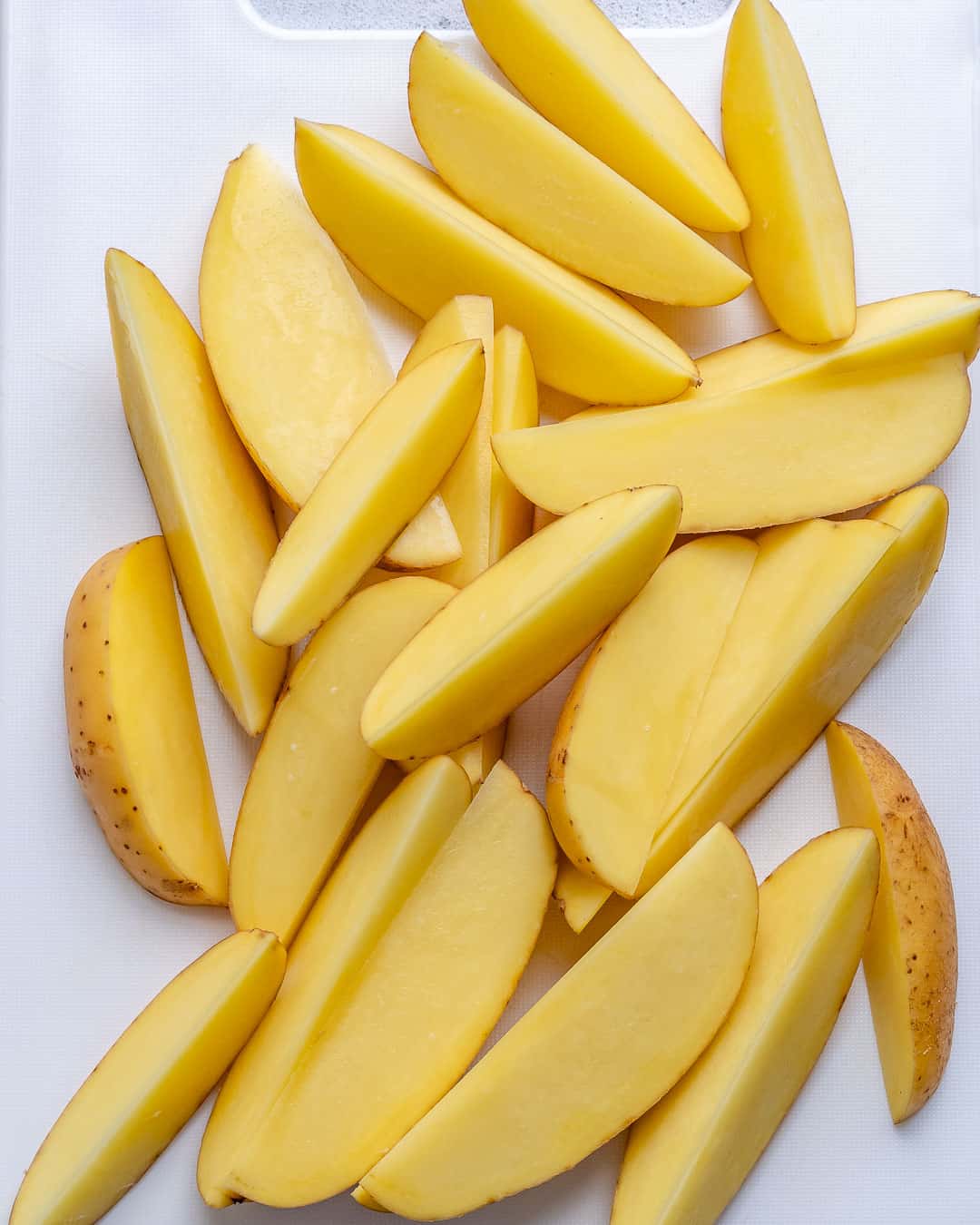 chopped potato wedges on a cutting board.