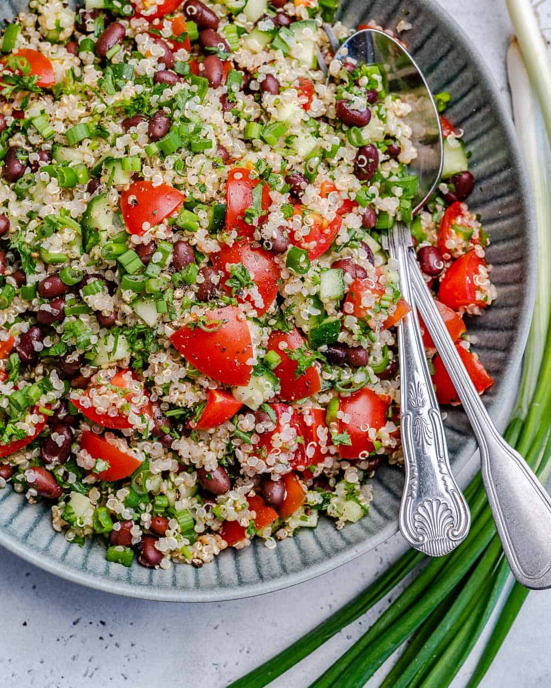 top view of tabbouleh on blue plate with spoon and fork in salad 