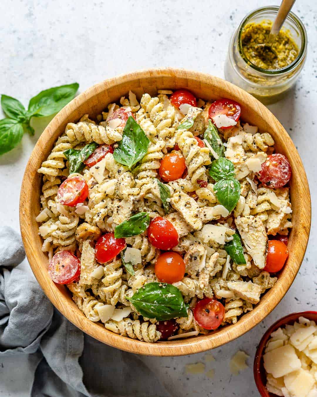 top view of pasta salad with pesto and parmesan cheese on the side 