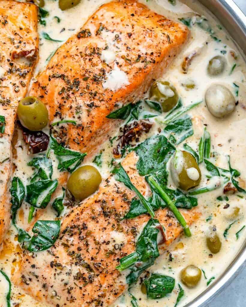close up of a healthy Tuscan salmon recipe on a pan made with spinach and olives 