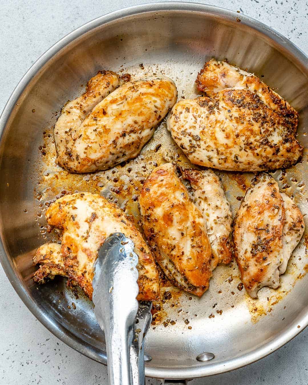 cooking chicken in a pan to make chicken caesar salad.