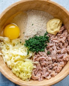 ingredients for the tuna patties in a brown bowl, egg, almond flour, mozzarella cheese, tuna, dill, and mustard.