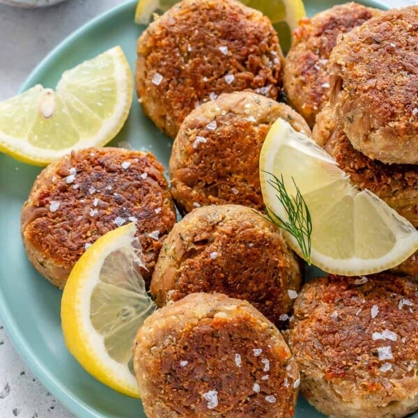tuna patties on a blue plate with lemon wedges
