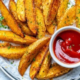 top view of baked potato wedges with a side of ketchup in a small white bowl.