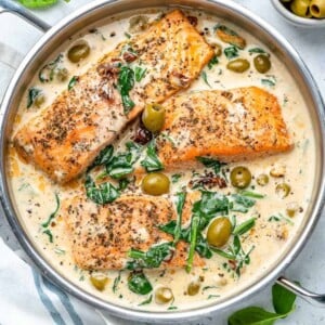 top view of Creamy Tuscan salmon filets in pan in a creamy Tuscan sauce with spinach and olives