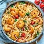 top view of shrimp and spaghetti in pan with tomato and spinach