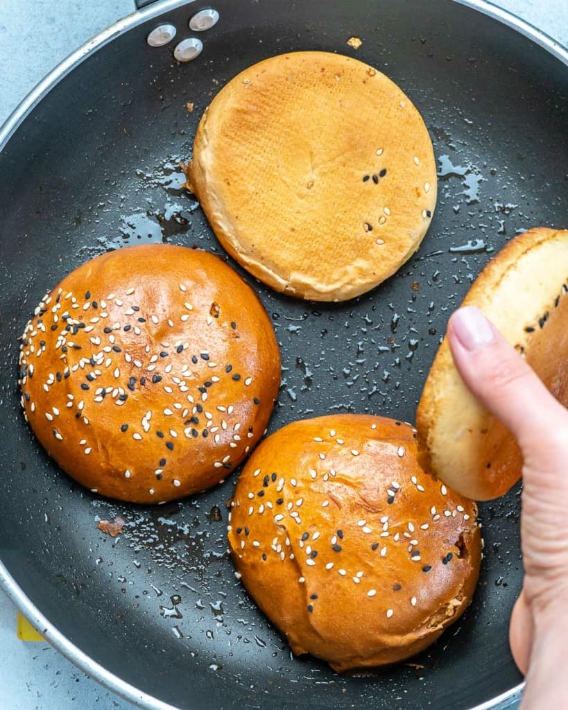 burger buns being cooked over a skillet 