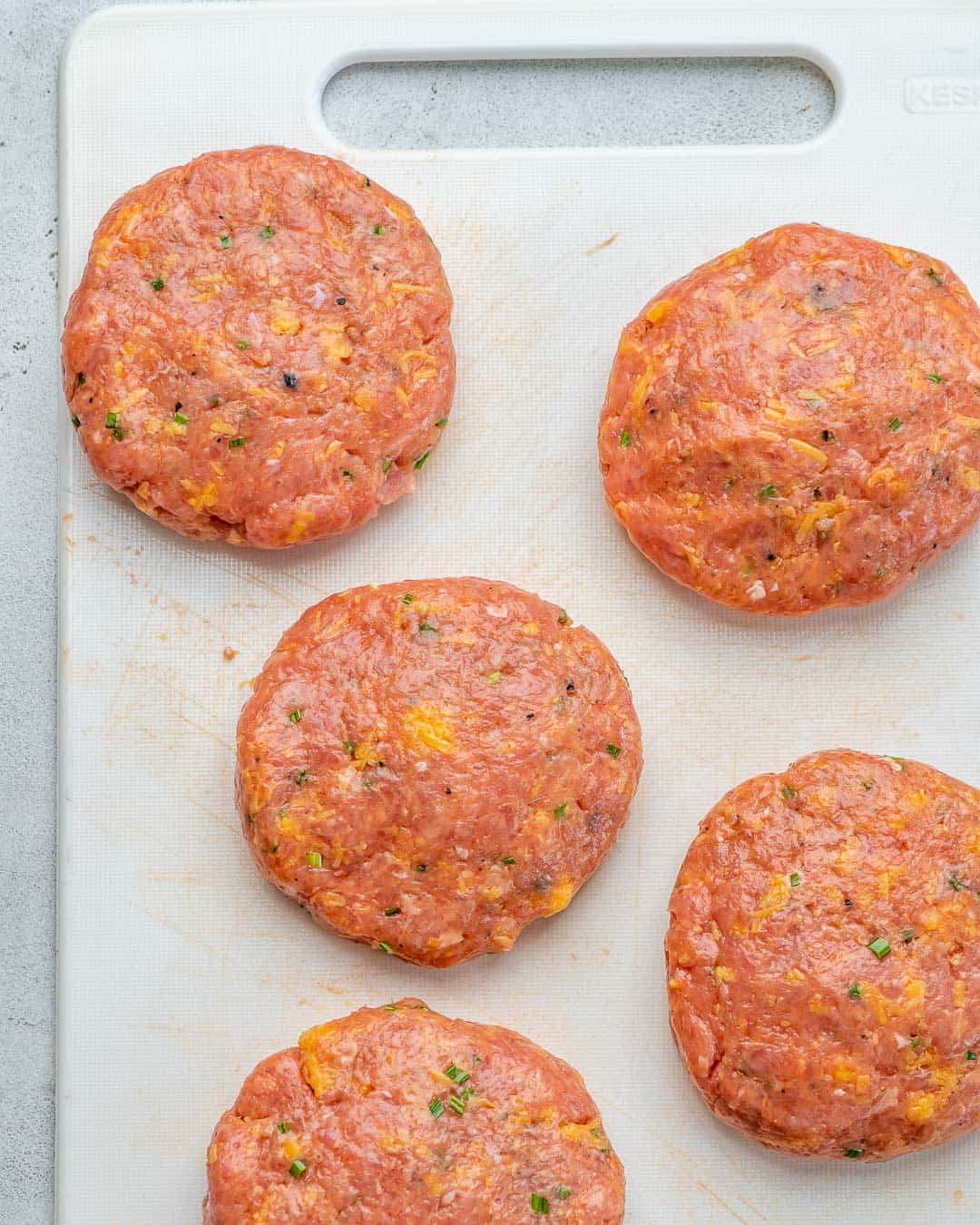 uncooked chicken patties on a cutting board.