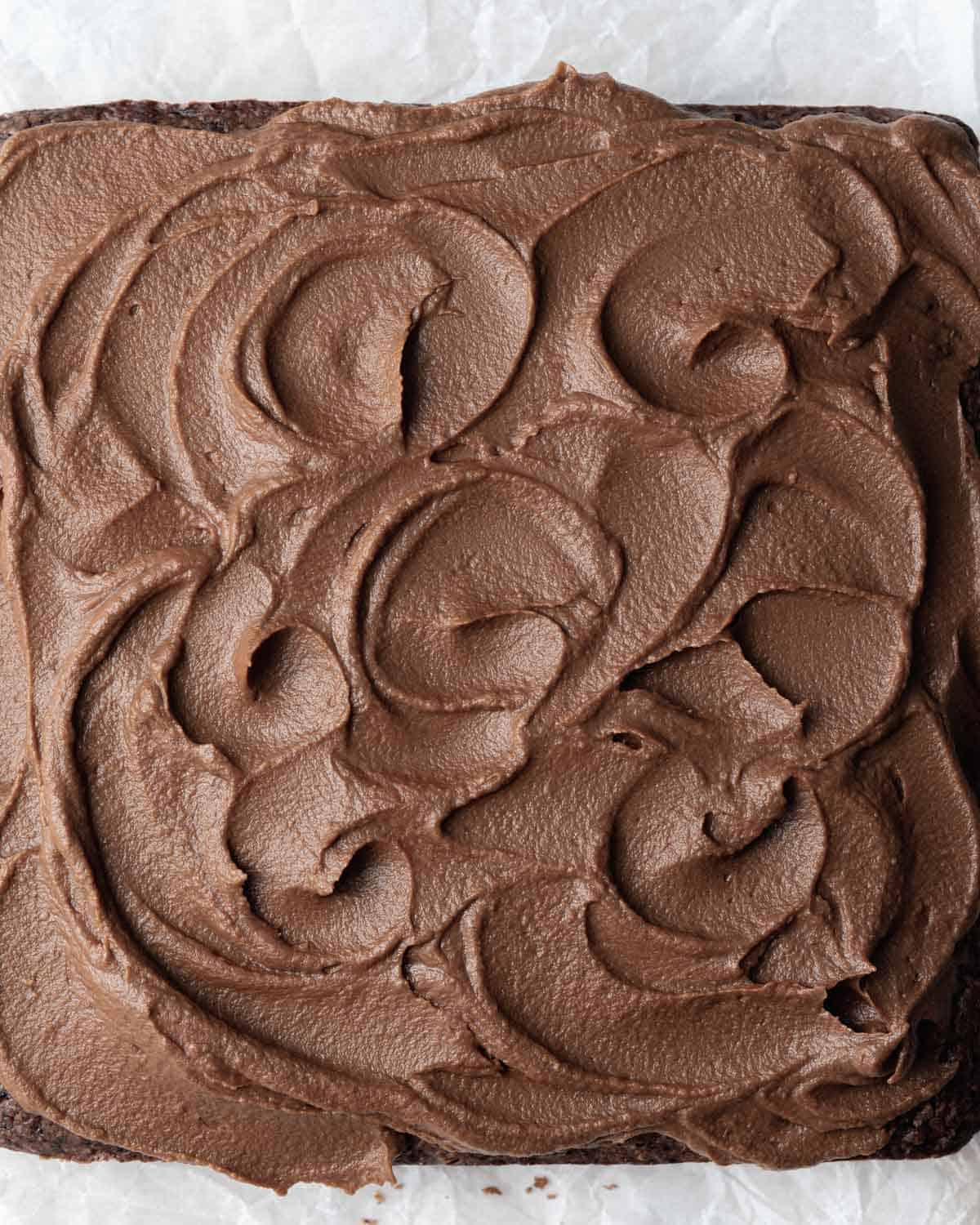 chocolate cake square before cutting it topped with a healthy chocolate frosting.