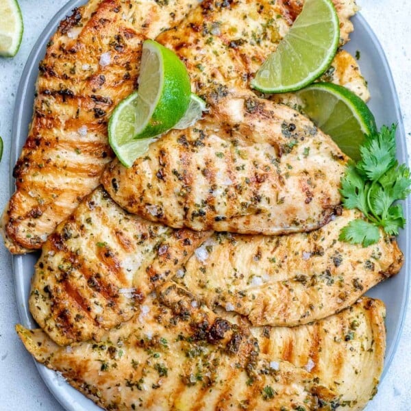 grilled chicken breasts on a plate garnished with lime wedge.