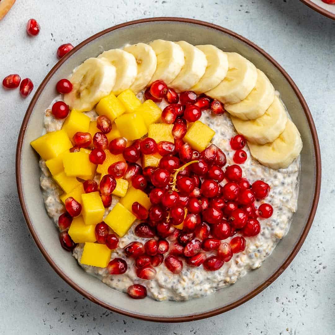 top view of oatmeal in a bowl with banana mango and pomegranate toppings