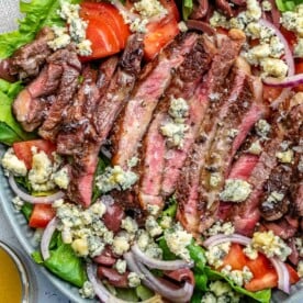 top view of a salad with sliced cooked steak topped with blue cheese