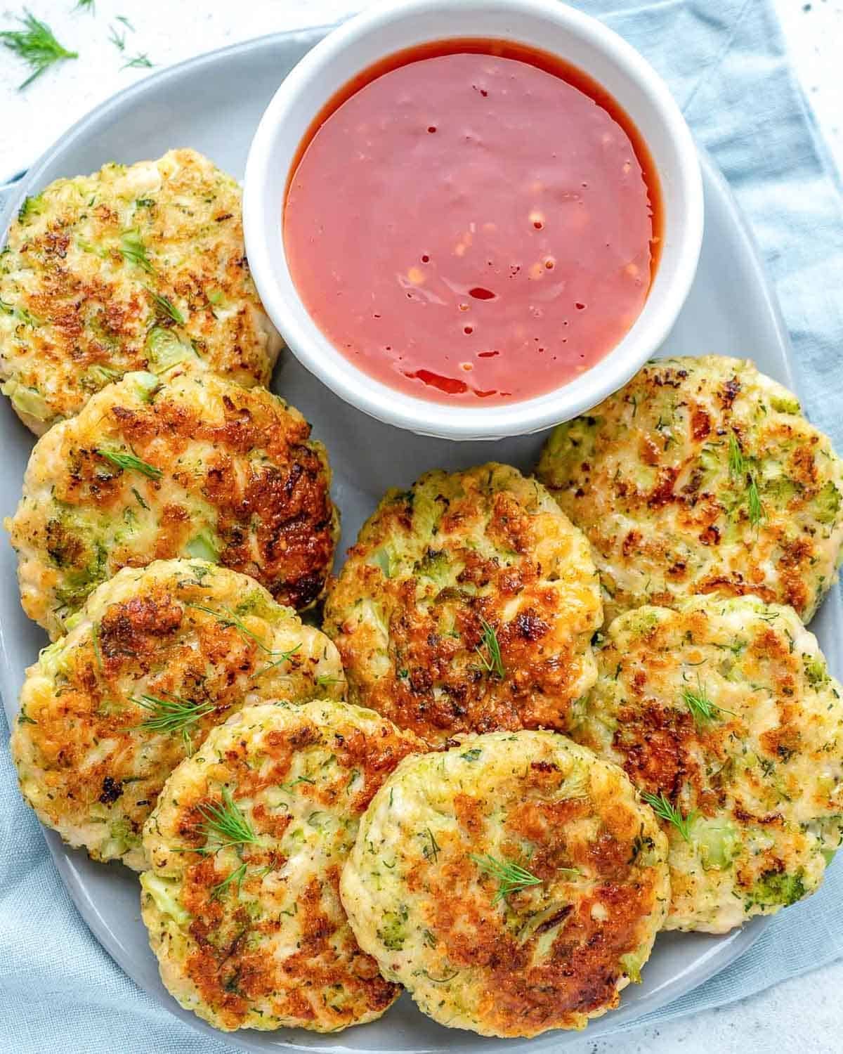 chicken patties on a platter next to a small bowl of sweet chili sauce.