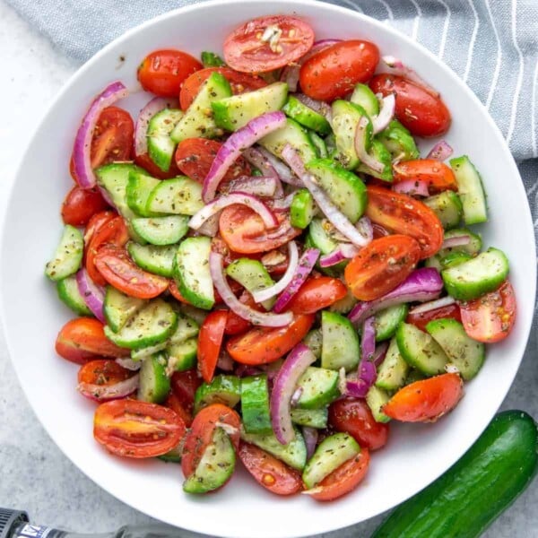 salad made from tomatoes, cucumber, and onions in a round white bowl.