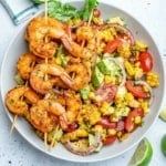 top view of corn salad with 3 skewers of grilled shrimp over salad