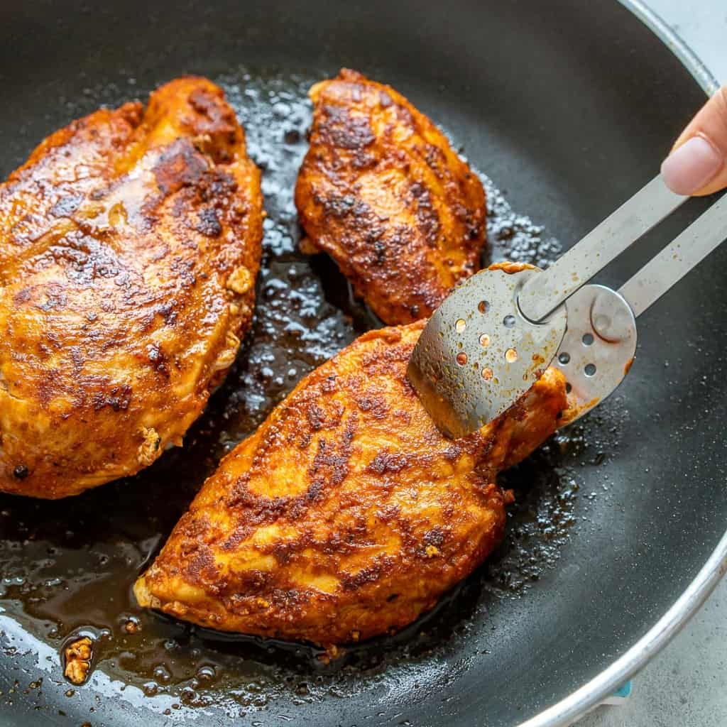 Pan-fried seasoned chicken breast on a black skillet