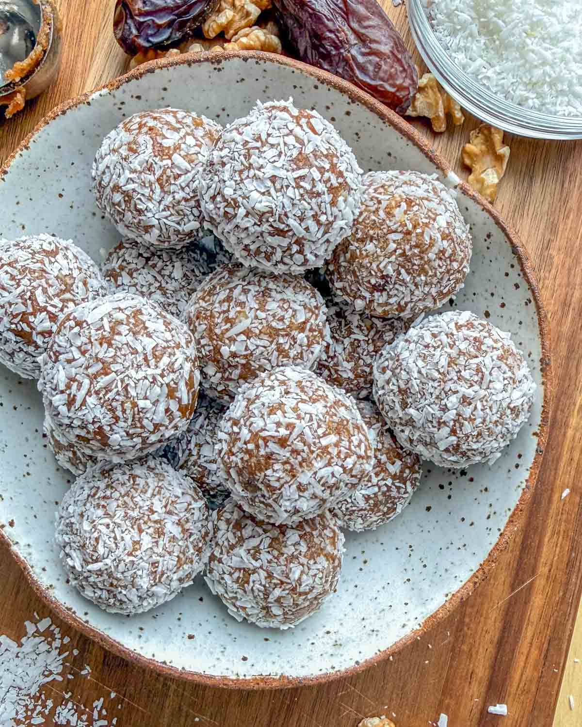 Date energy balls rolled in shredded coconuts in a bowl.