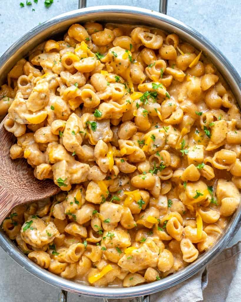 top view chicken mac and cheese in skillet with wooden spoon