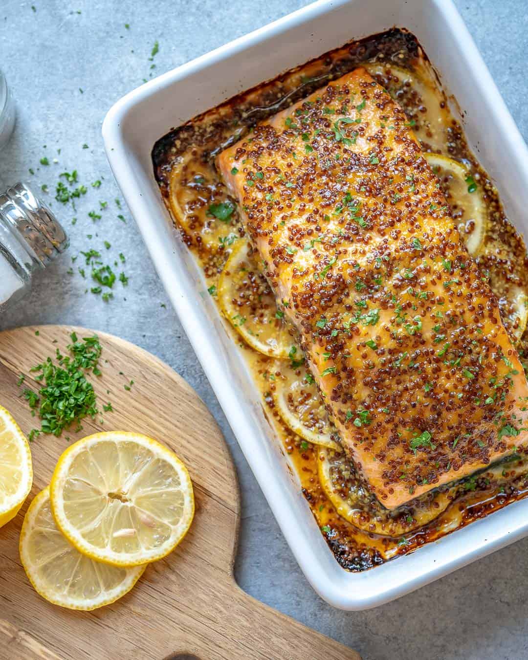 baked salmon in dish with lemon wedges on the left side 