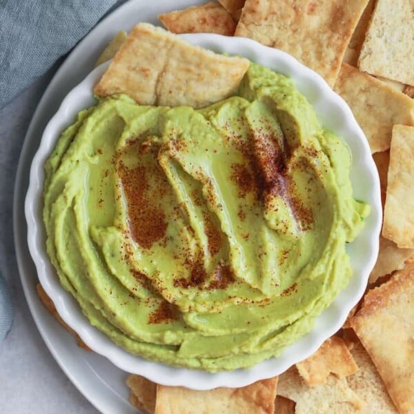 top view of hummus in white bowl with pita chips for serving