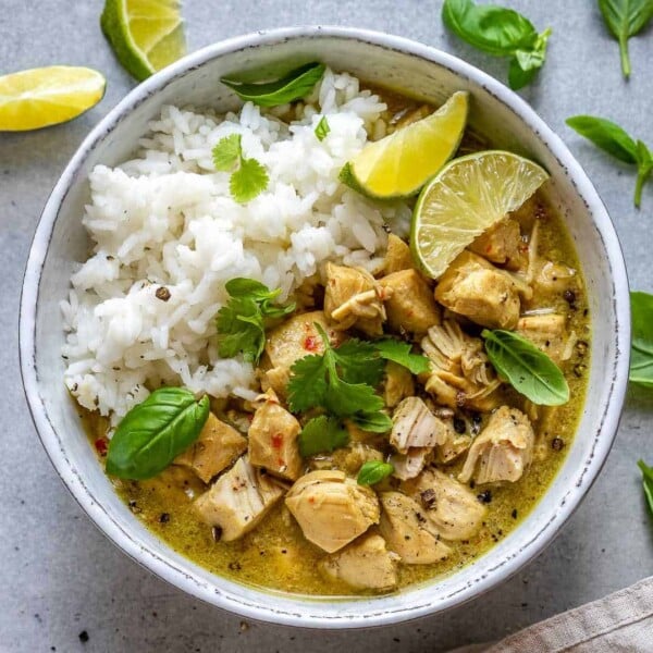 A round white bowl of chicken green curry with white rice.