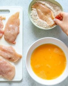 Dredging chicken in flour and egg wash.
