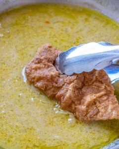 adding the cooked chicken in lemon sauce in a skillet.