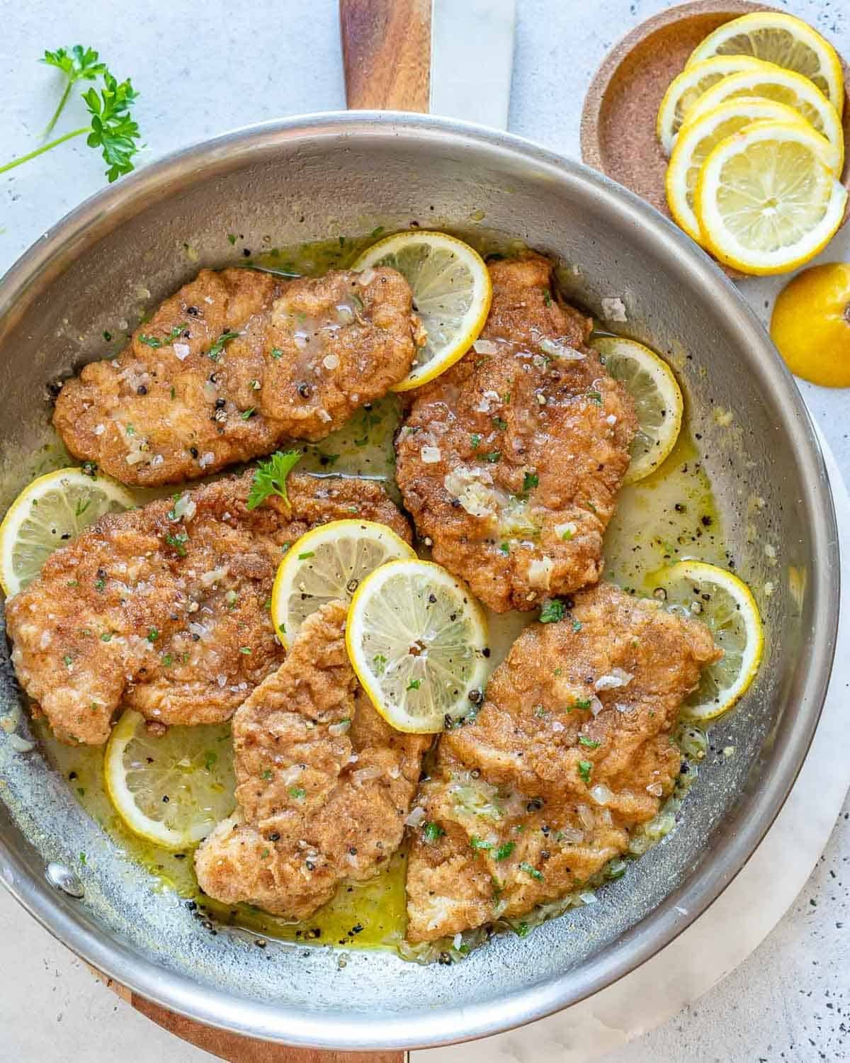 a skillet with crispy chicken cooked in a lemon sauce.