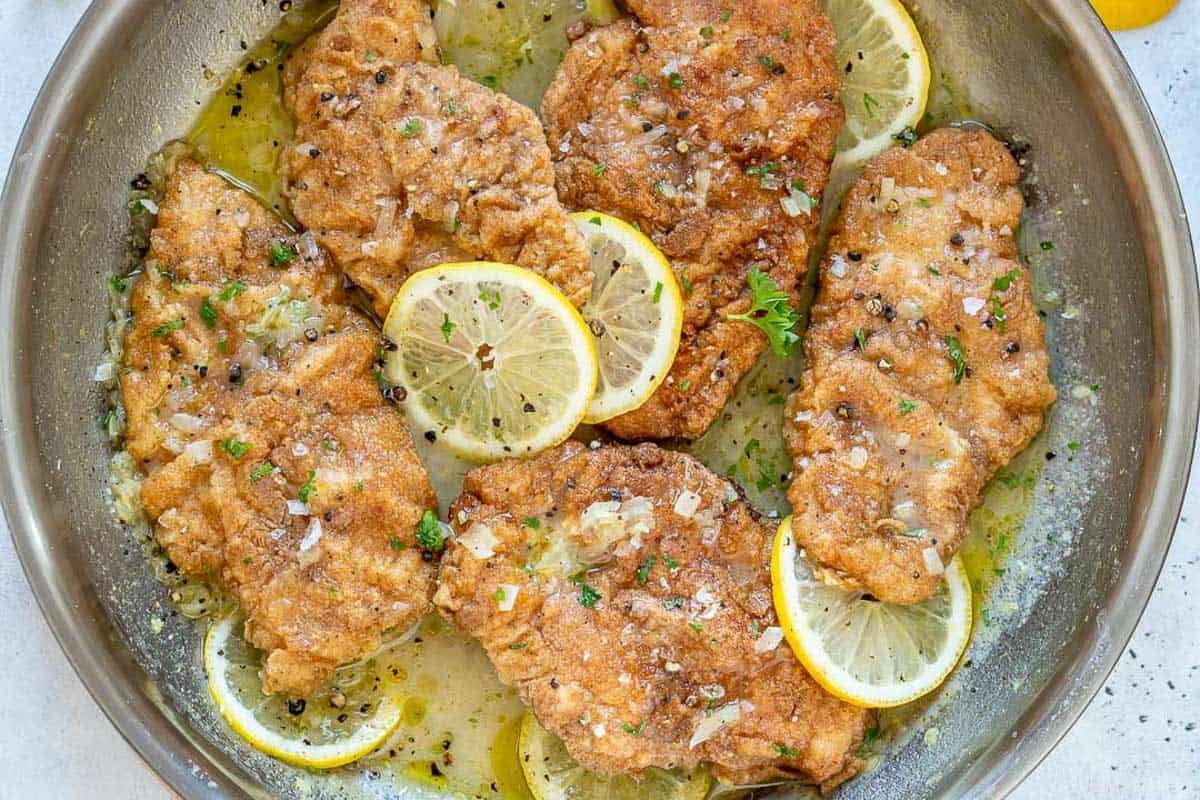 Crispy chicken cooked in a lemon sauce in a skillet.
