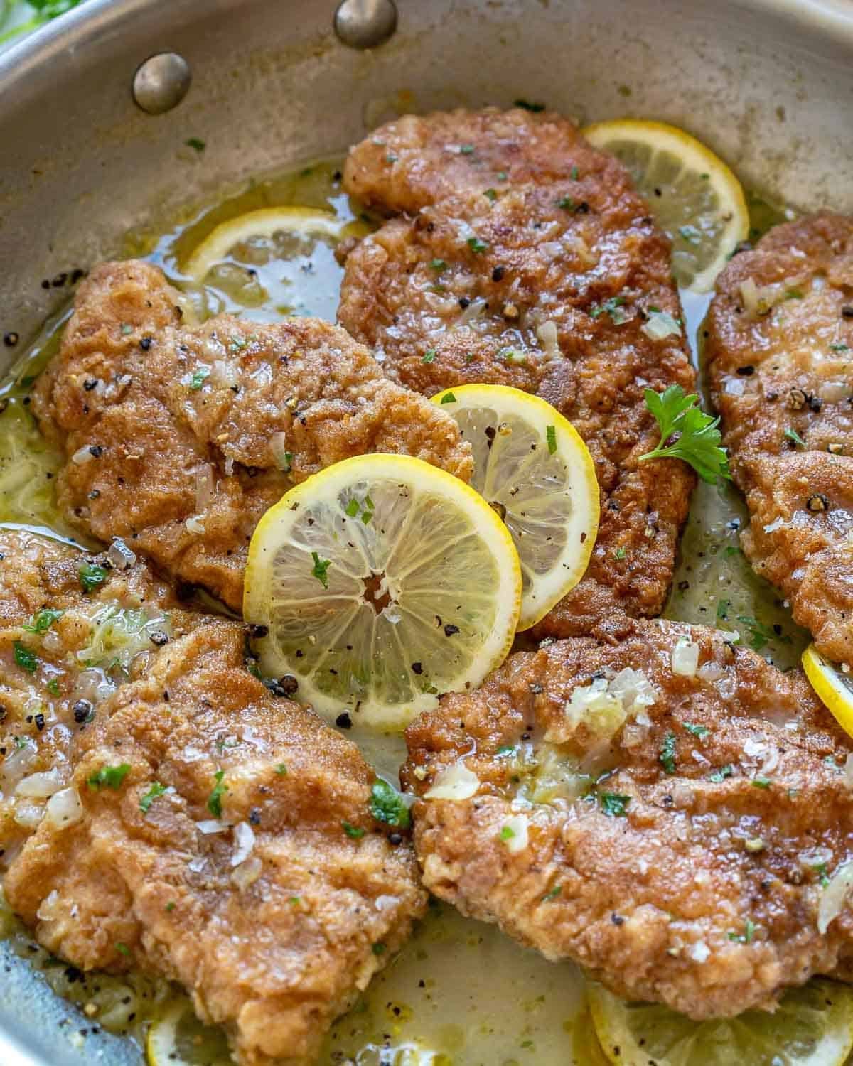 Cooked crispy chicken in a lemon sauce in a skillet.