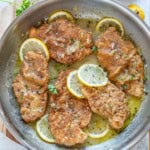 chicken francese cooked in a pan with lemon sauce.