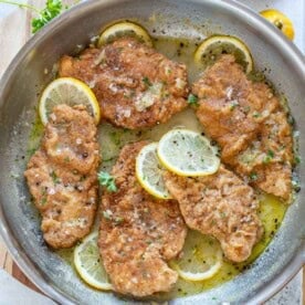 chicken francese cooked in a pan with lemon sauce.
