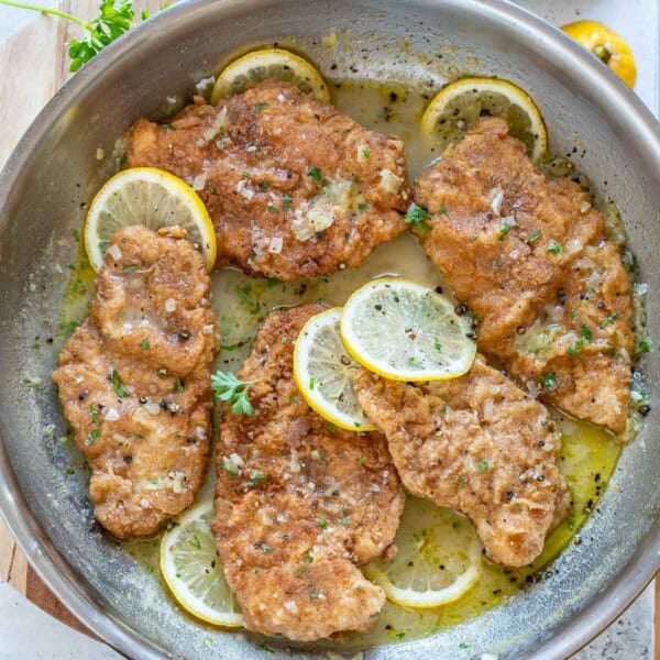 chicken francese cooked in a pan with lemon sauce.