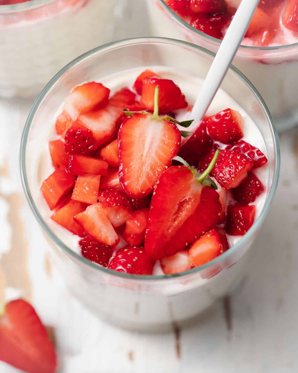 a cup with no-bake cheesecake topped with fresh chopped strawberries.