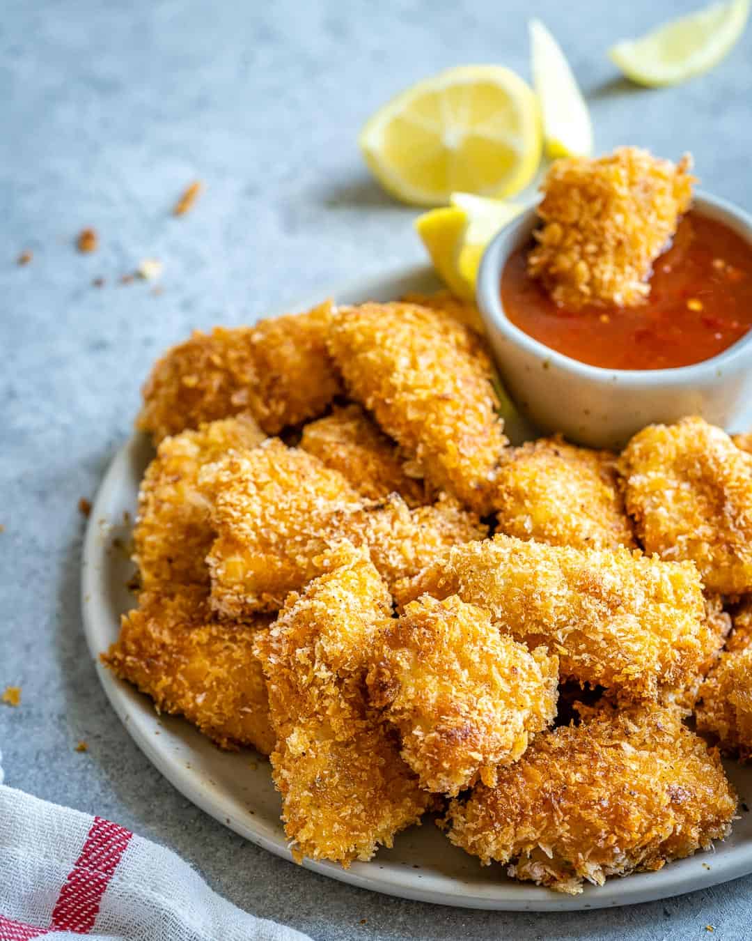 Chicken nuggets on plate and one in bowl of ketchup.