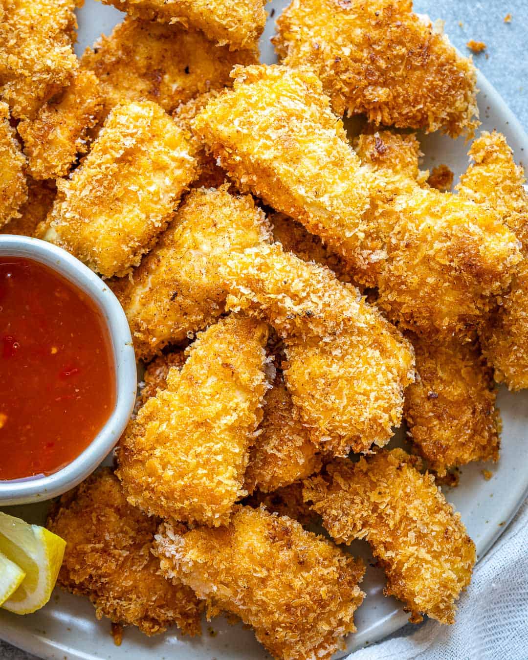 Close top view of chicken nuggets on white plate with ketchup