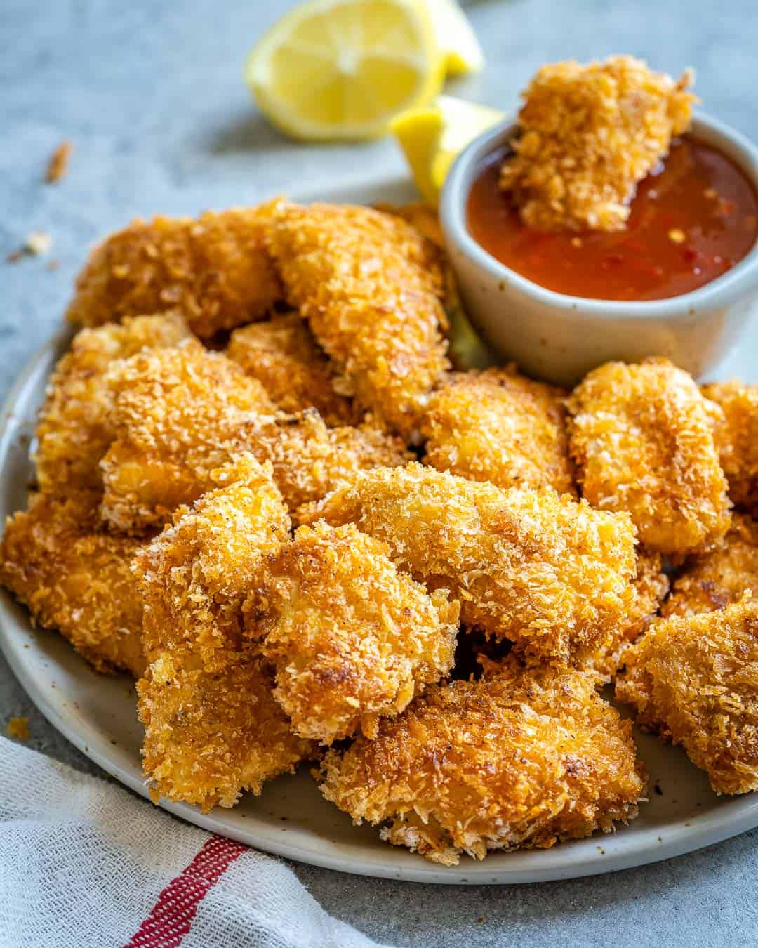 Air fryer chicken nuggets piled on plate with bowl of ketchup