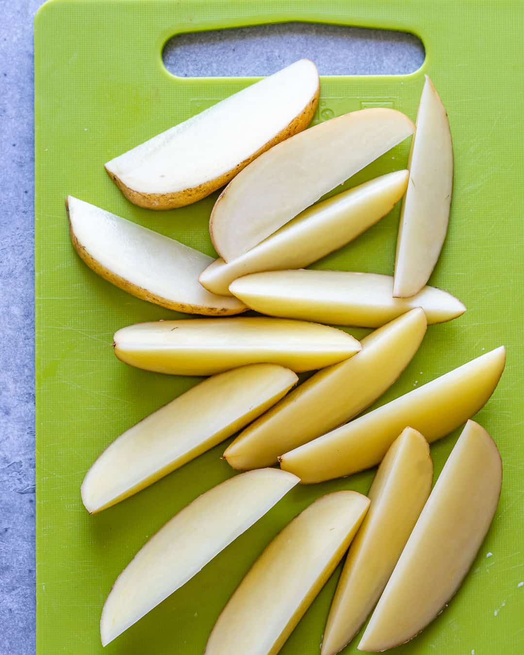 Potatoes washed and cut into wedges on cutting board