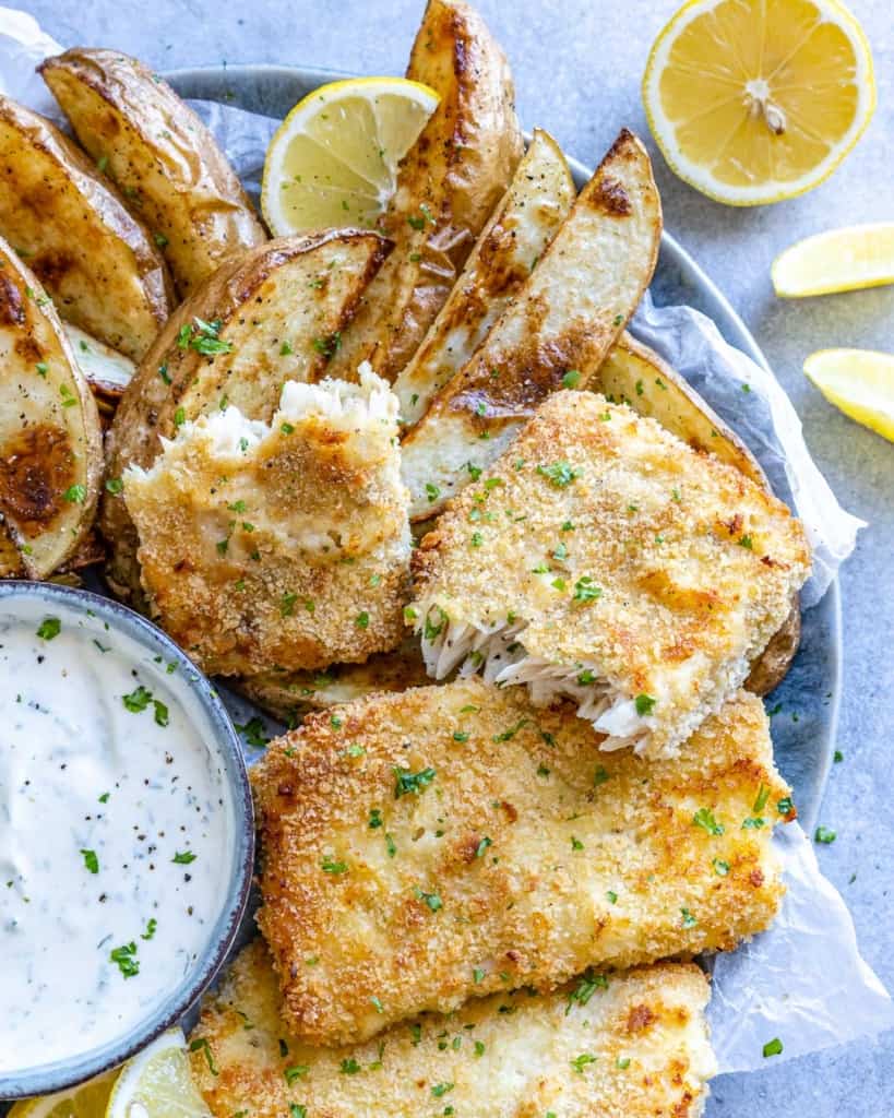 side shot of air fryer fish with ranch dip dressing and potato wedges