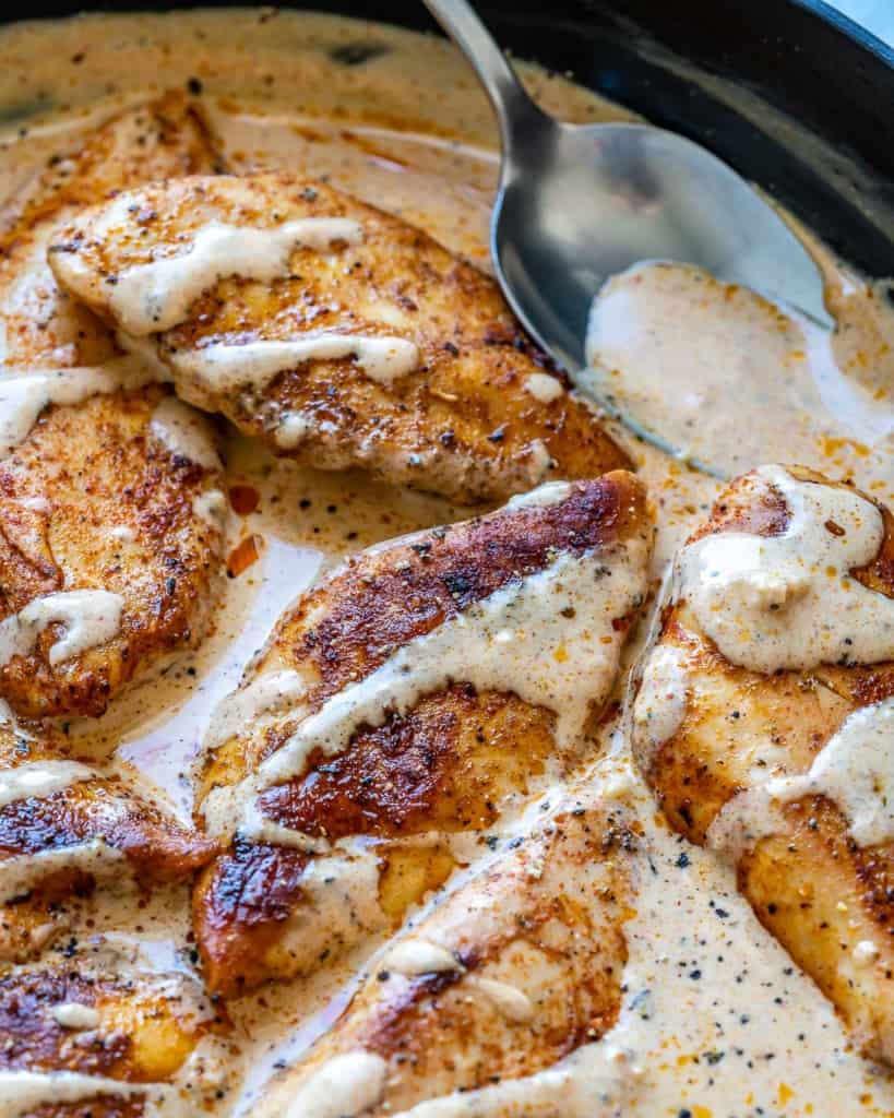 spoon of creamy sauce in chicken pan 