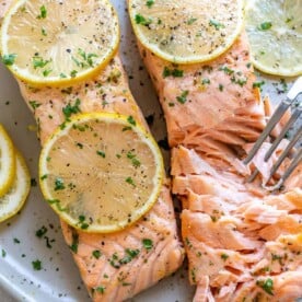 two baked salmon on plate with fork flaking it