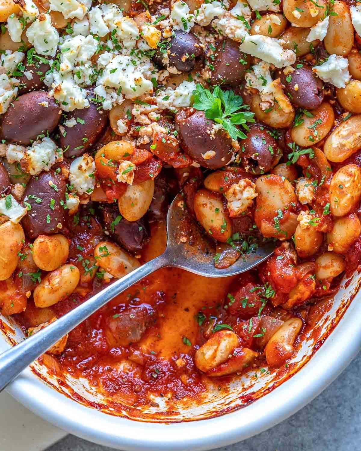 dish with Greek baked beans with a spoon dipped in.