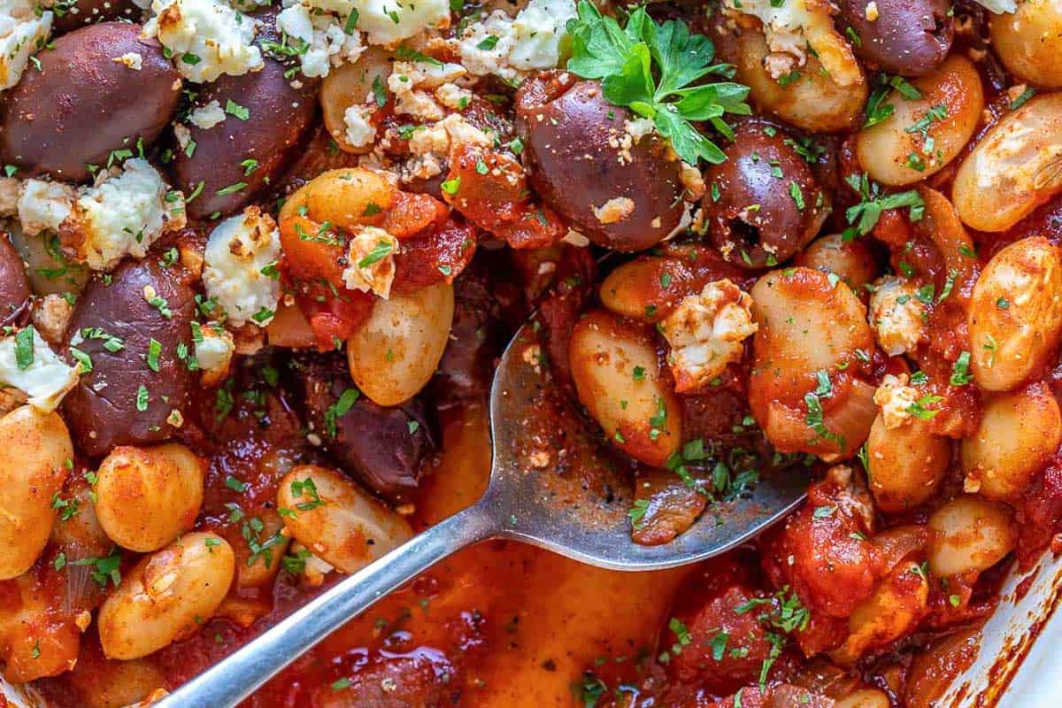baked beans in a dish soaked in tomato sauce with spoon in the dish.