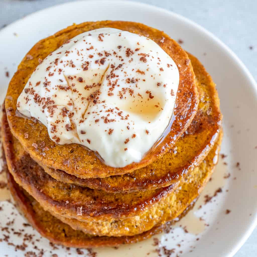 top view of pumpkin pancakes topped with yogurt maple syrup and cinnamon