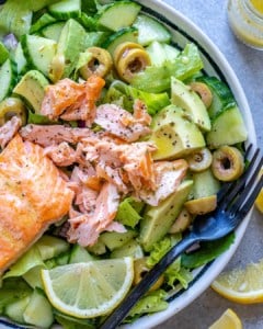 a salad bowl topped with cooked flaked salmon.